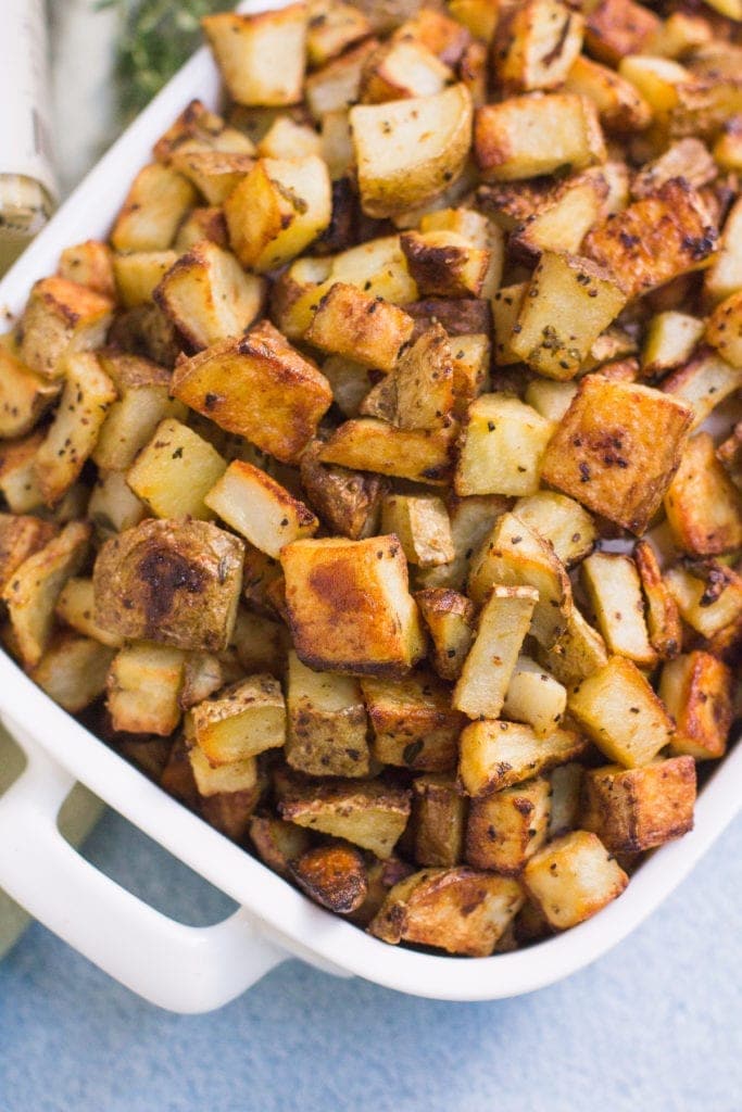 Crispy Dijon Roasted Potatoes in a hite bowl with a blue background