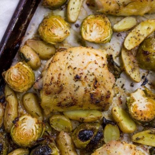 Sheet Pan Lemon Rosemary Chicken Thigh Dinner coming out of the oven on a black baking sheet.