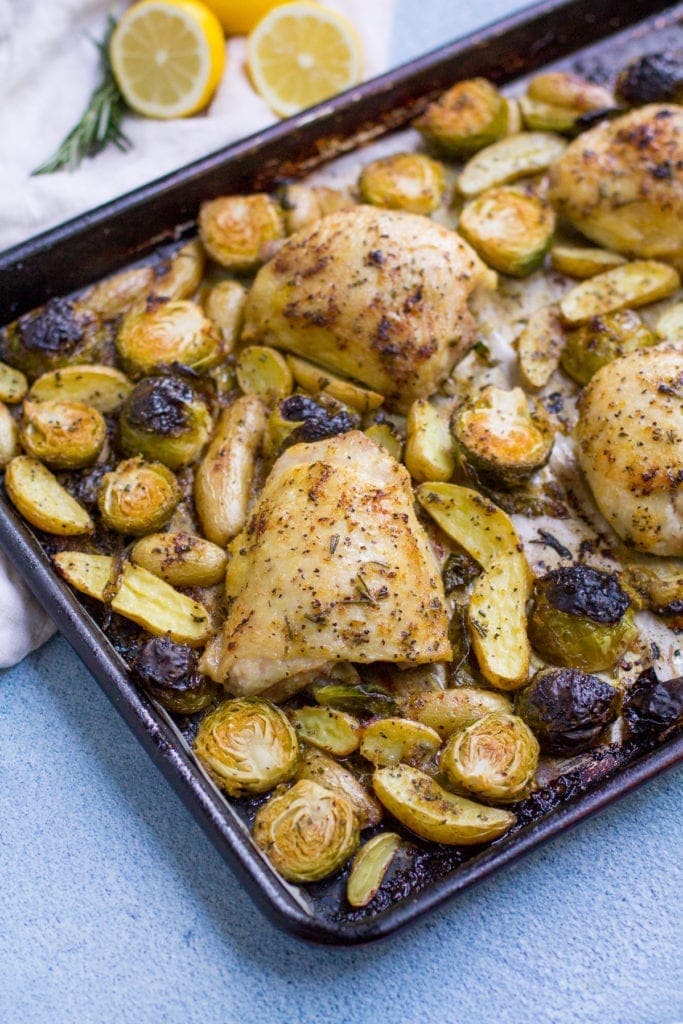 Sheet Pan Lemon Rosemary Chicken Thigh Dinner out of the oven on a blue background.
