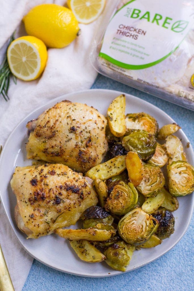 Sheet Pan Lemon Rosemary Chicken Thigh Dinner on a white plate with Just BARE chicken thighs package, lemon, rosemary off to the side.