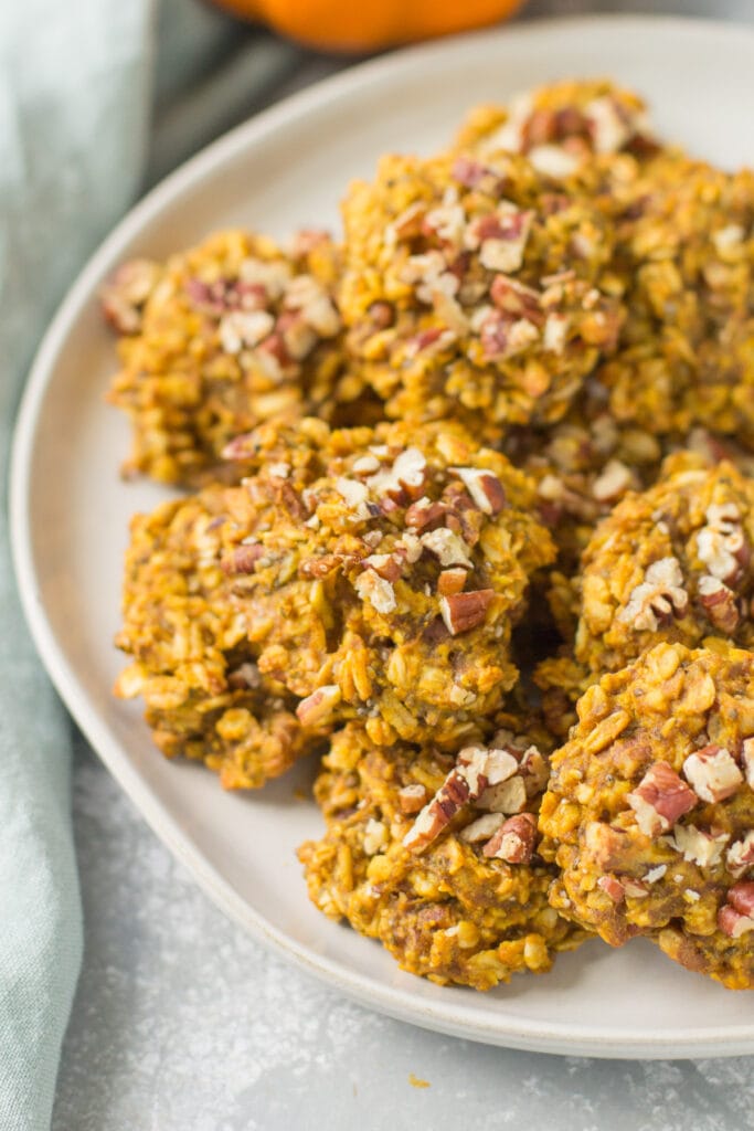 An overhead photo of pumpkin breakfast cookies on a white plate with a blue napkin in the background