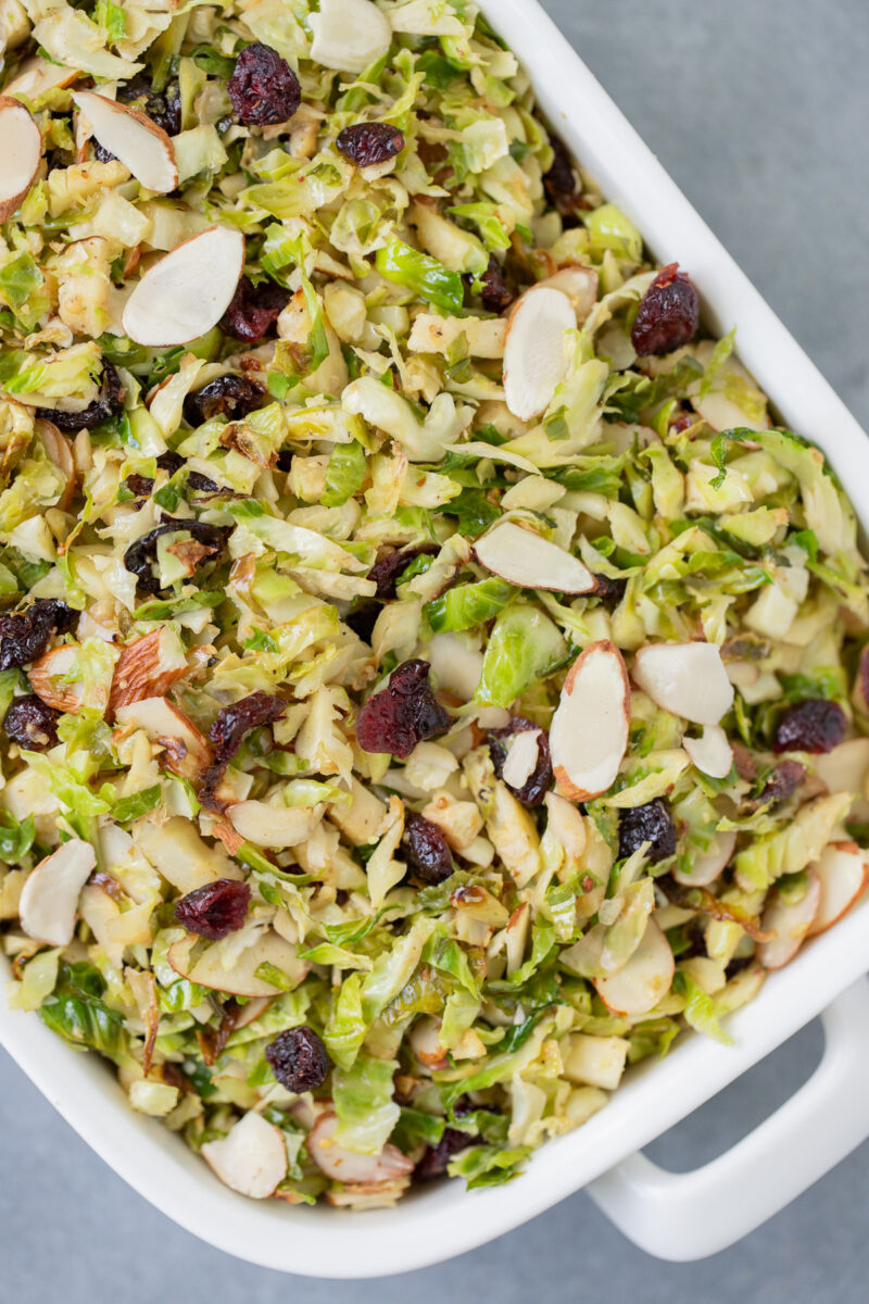 Shaved Brussels Sprouts Salad in a white dish on a grey background