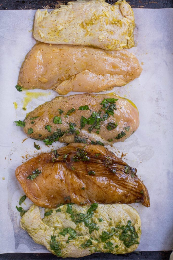 5 Healthy Chicken Marinades on a parchment lined baking sheet