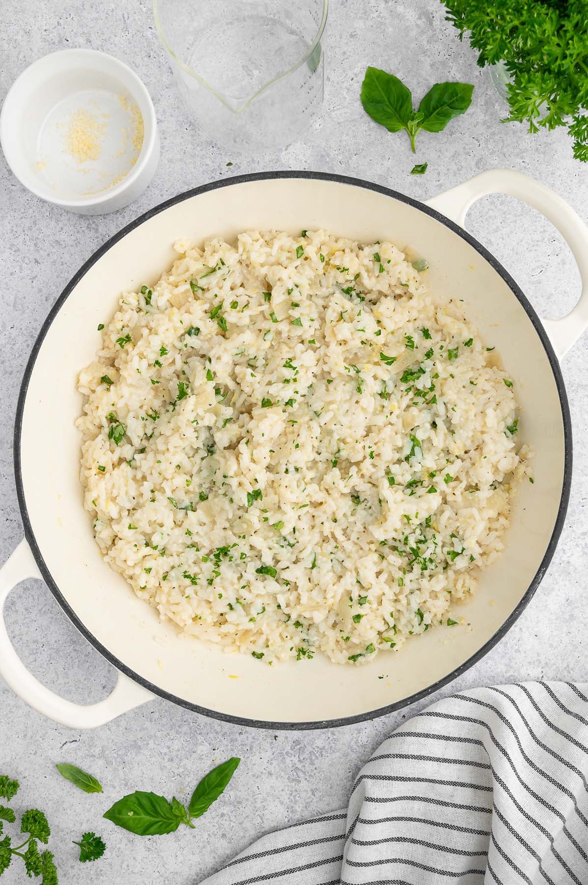 Overhead view of cooked lemon risotto garnished with fresh herbs in a large pot.