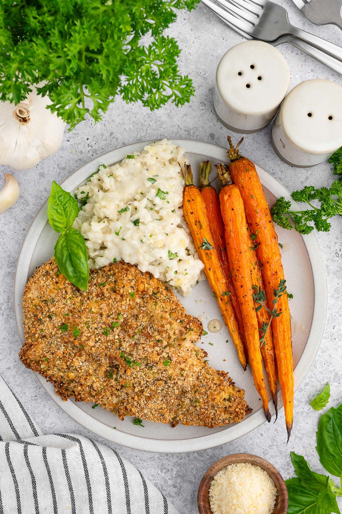 A plated dinner of baked chicken cutlet, roasted carrots, and creamy lemon rice.