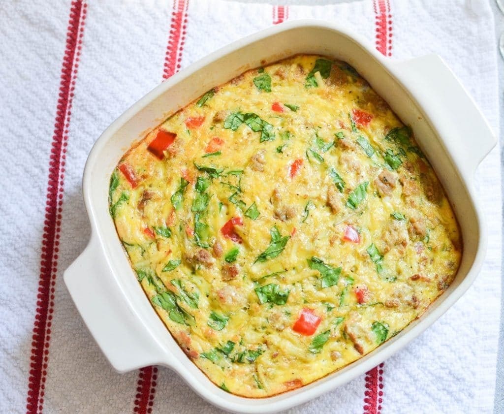 A paleo breakfast casserole in a white dish on a red and white striped background