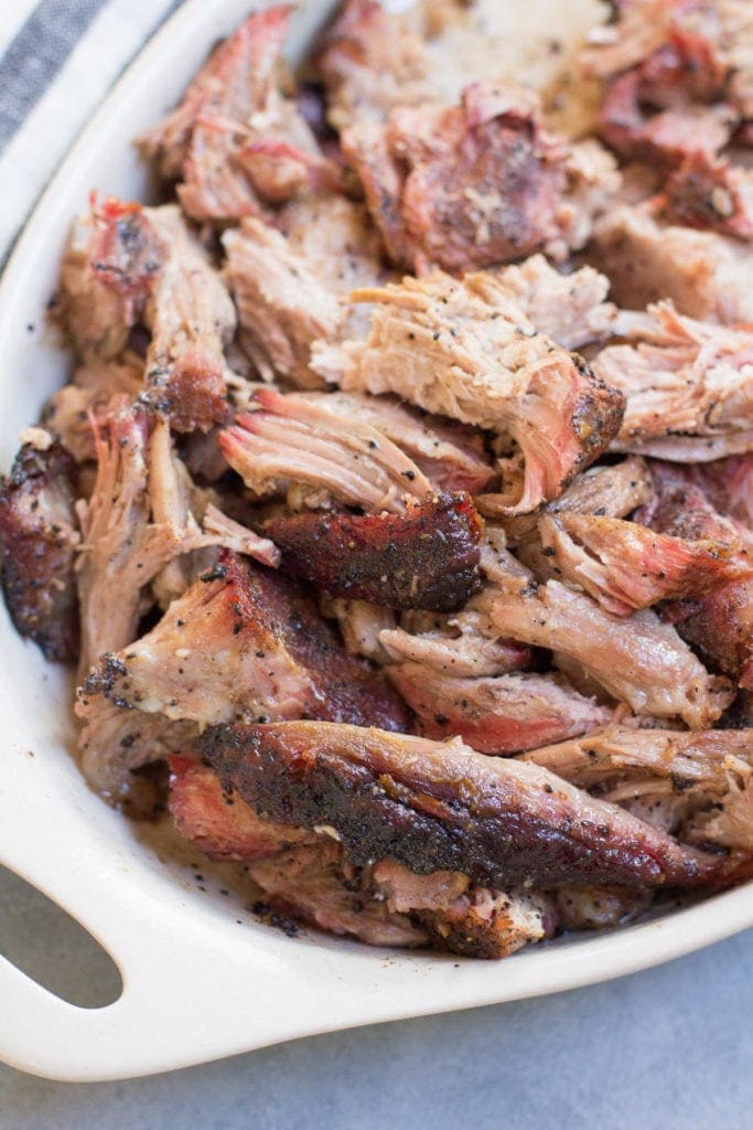 a close up shot of Coffee BBQ Pulled pork in a white bowl on a grey background.