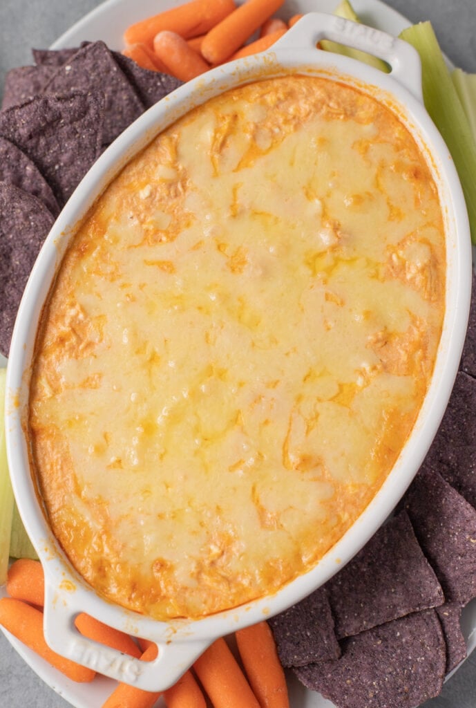 A close up of simple buffalo chicken dip in a white bowl on a platter