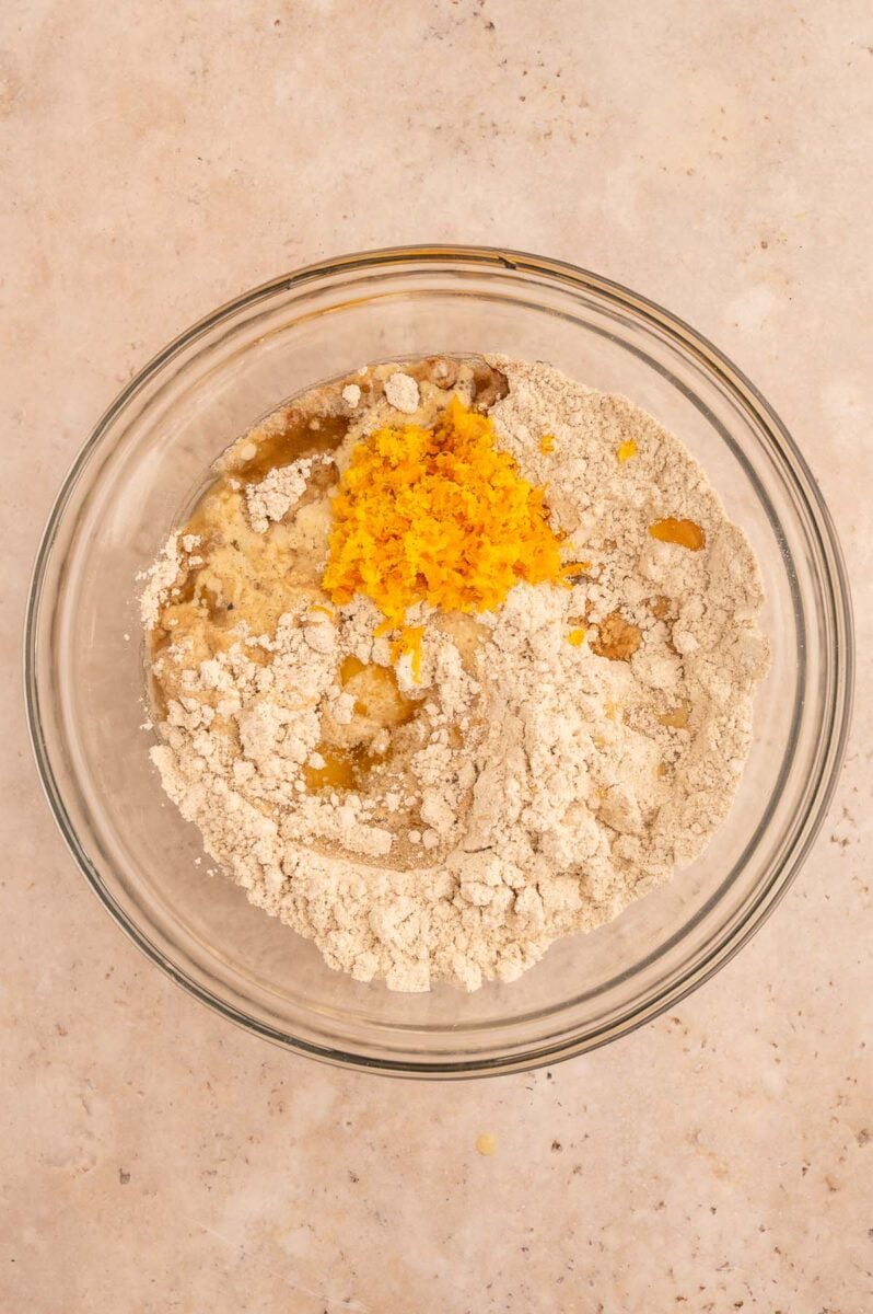 Ingredients for cranberry orange muffins in a clear bowl before mixing together.