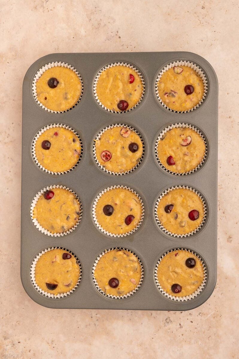 Unbaked cranberry orange muffins in a muffin tin.