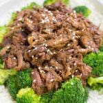 Healthy Slow Cooker Beef + Broccoli over cauliflower rice in a white bowl.