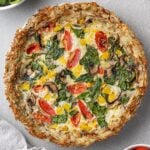 An overhead image of Potato Crust Quiche on a grey background with a white linen