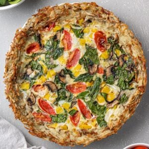 An overhead image of Potato Crust Quiche on a grey background with a white linen
