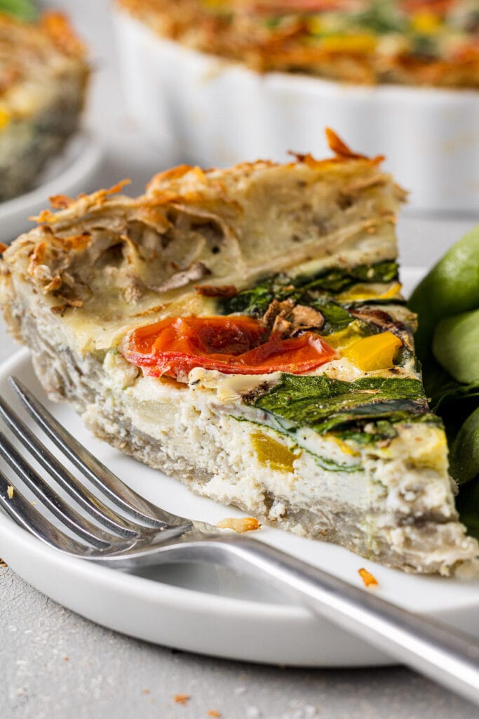 A slice of potato crust quiche with a bite being taken out of it.