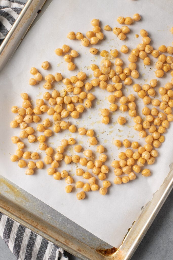 Chickpeas on a parchment lined baking sheet before being baked in the oven