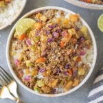 Ground Turkey Skillet in a white bowl with gold forks and a pan on the side on a grey background