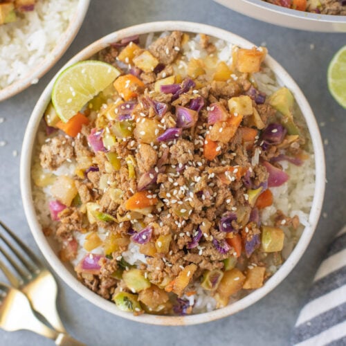 Ground Turkey Skillet in a white bowl with gold forks and a pan on the side on a grey background
