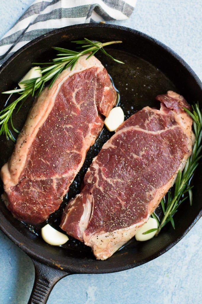 Steaks cooking in a cast iron skillet