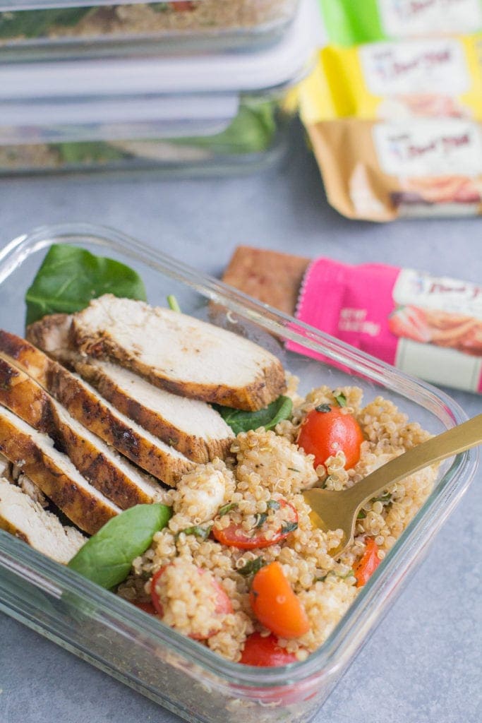 Chicken Caprese Quinoa Meal Prep Bowls with a gold fork taking a bite out of it + a granola bar off to the side