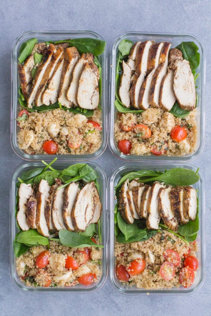 4 Chicken Caprese Quinoa Meal Prep Bowls laid out site by side on a grey background.