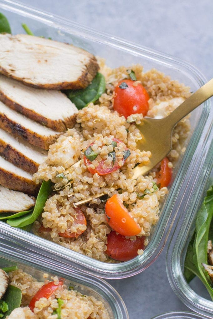 Chicken Caprese Quinoa Meal Prep Bowls with a gold fork taking a bite out of it