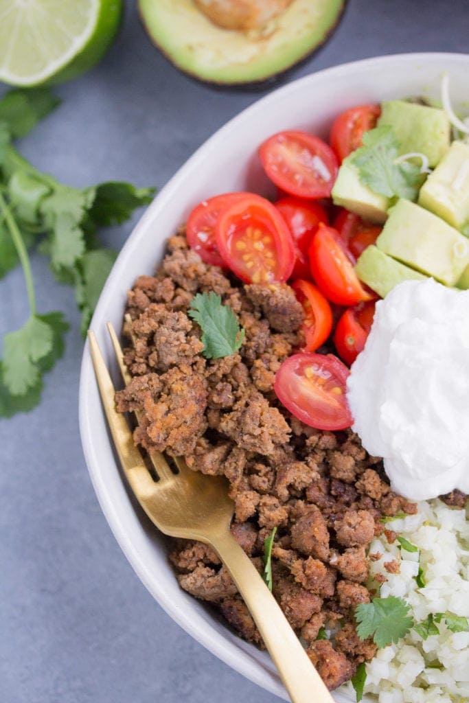 taco cauliflower rice bowls in a white bowl with a gold fork