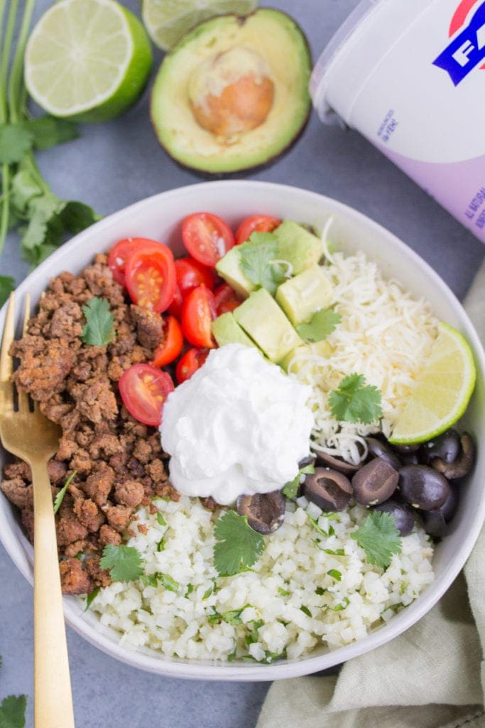 Low carb taco cauliflower rice bowls in a white bowl with a gold fork