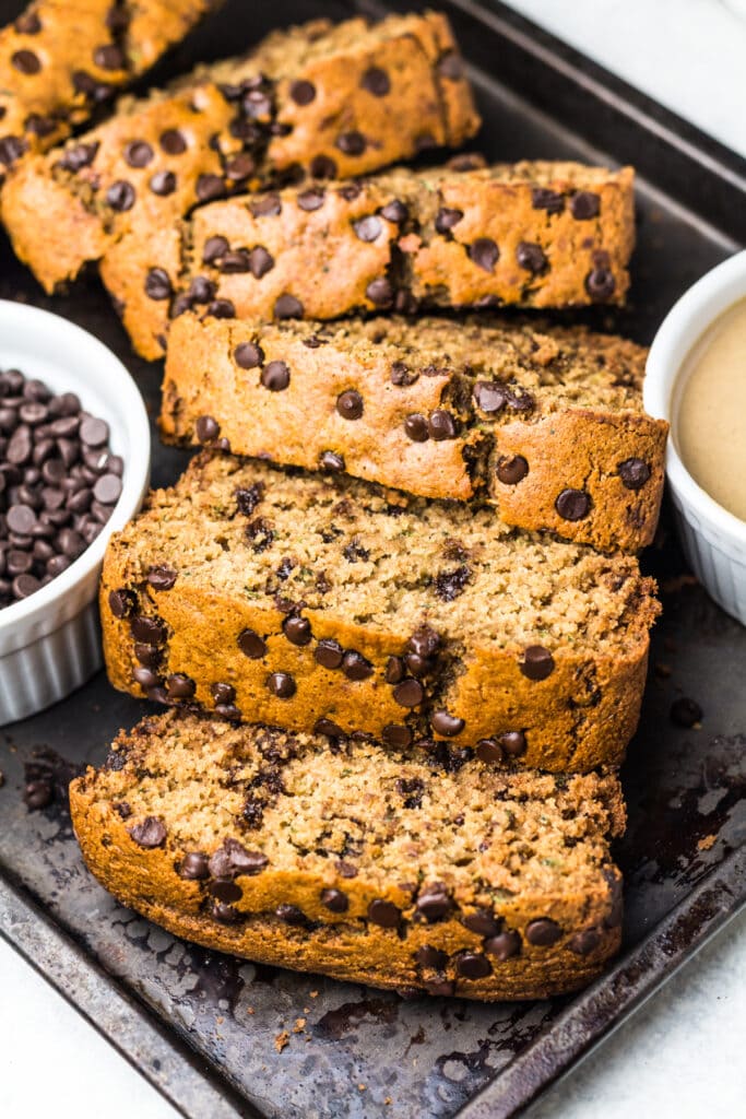 Slices of skinny bread made with zucchini and chocolate chips on a metal tray