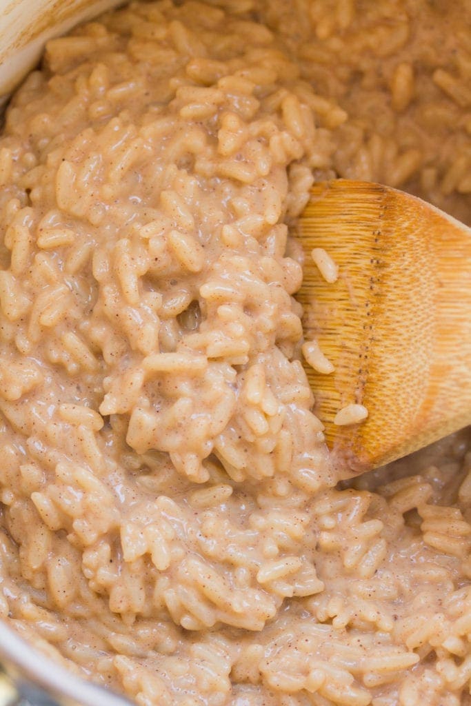 a pot filled with healthy rice pudding being stirred with a wooden spoon