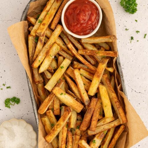 a platter piled with healthy baked french fries and a bowl of ketchup.