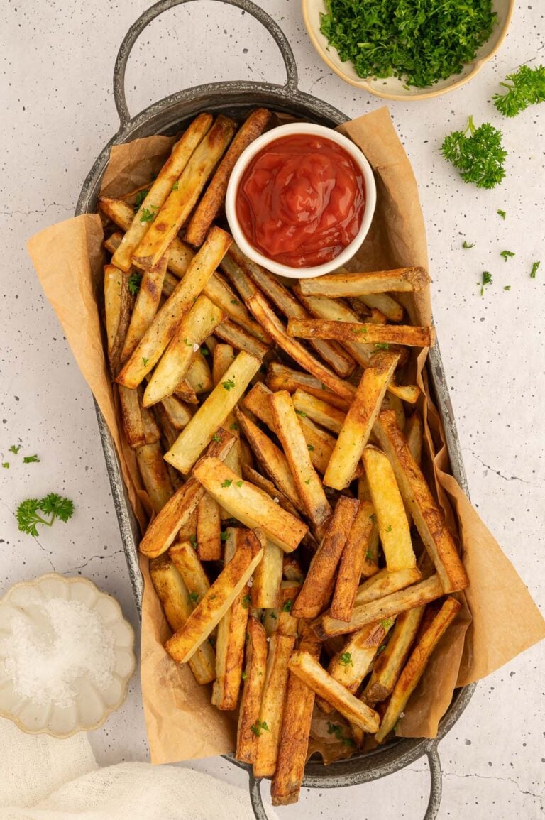 a platter piled with healthy baked french fries and a bowl of ketchup.
