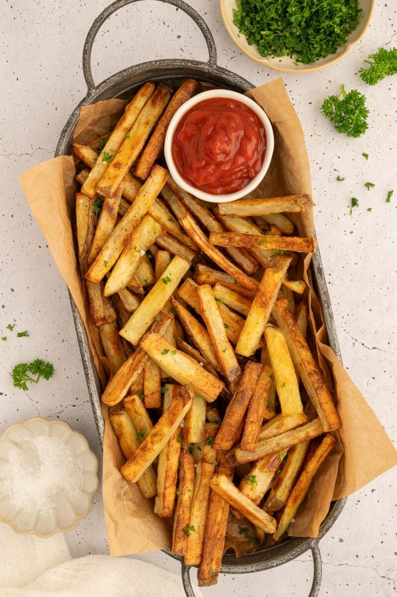 a platter piled with healthy baked french fries and a bowl of ketchup.
