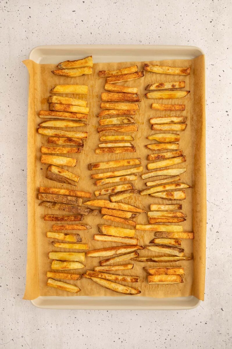 A baking sheet filled with healthy french fries right out of the oven.