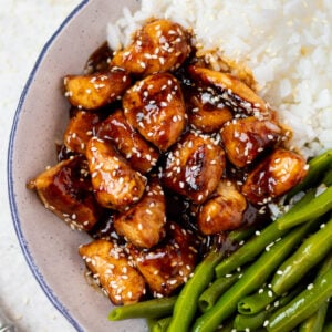 a grey plate with delicious healthy sesame chicken, white rice + green beans