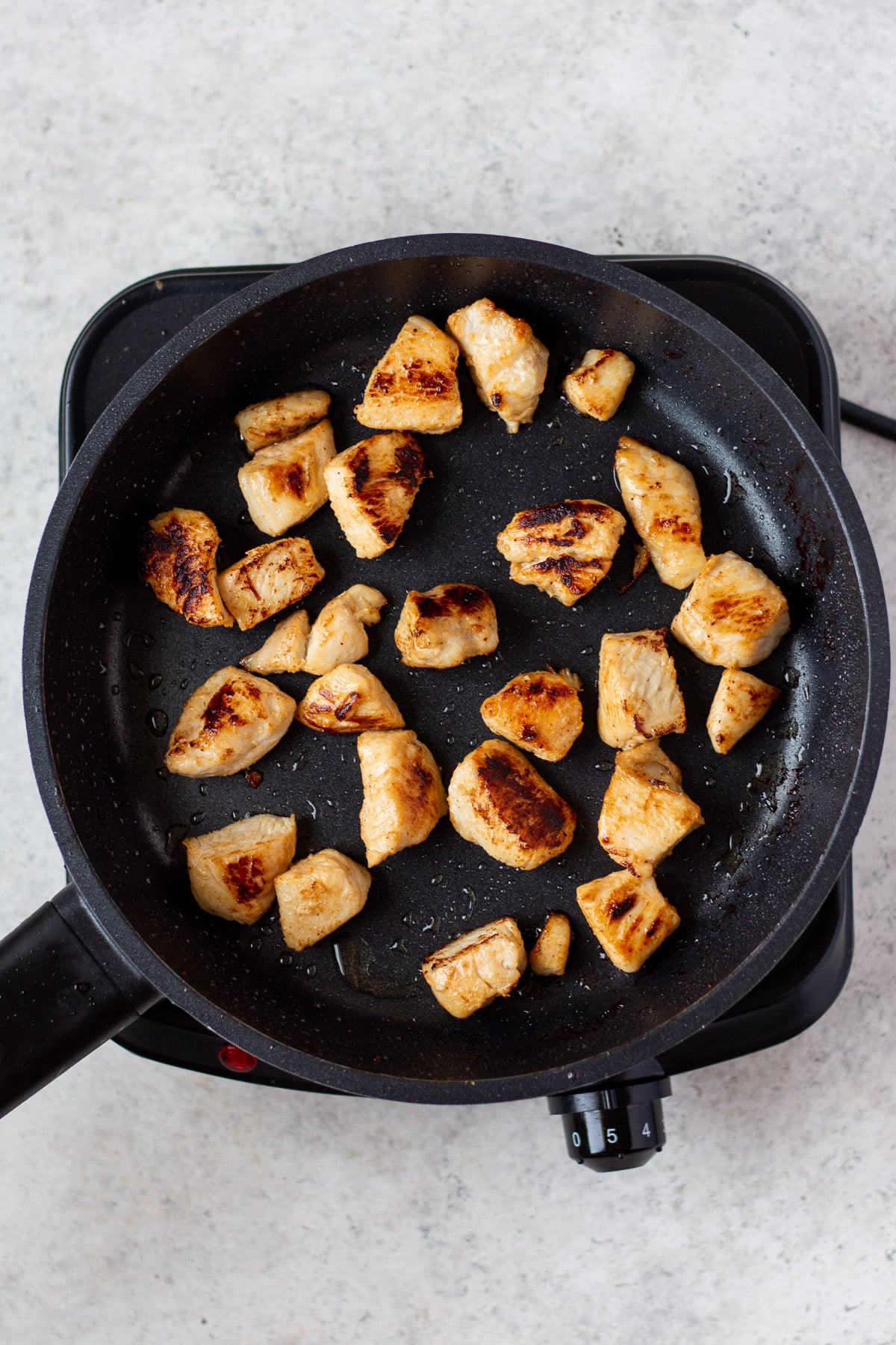 browned chicken in a cast iron pan for healthy sesame chicken