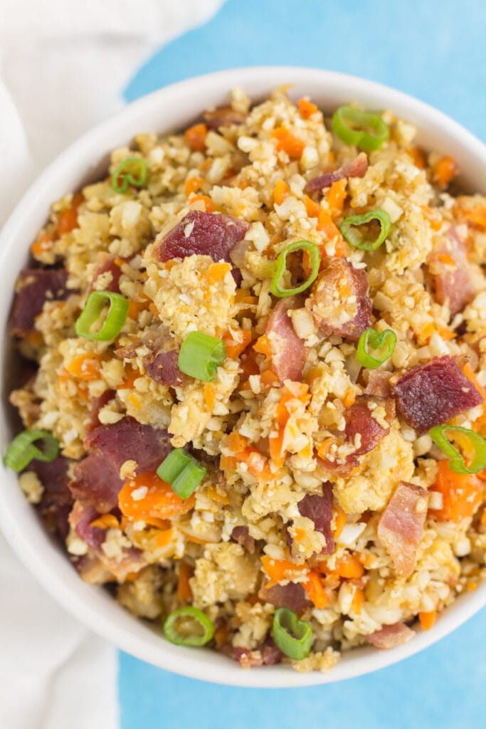 Breakfast Cauliflower Fried Rice in a white bowl on a blue background in a white bowl