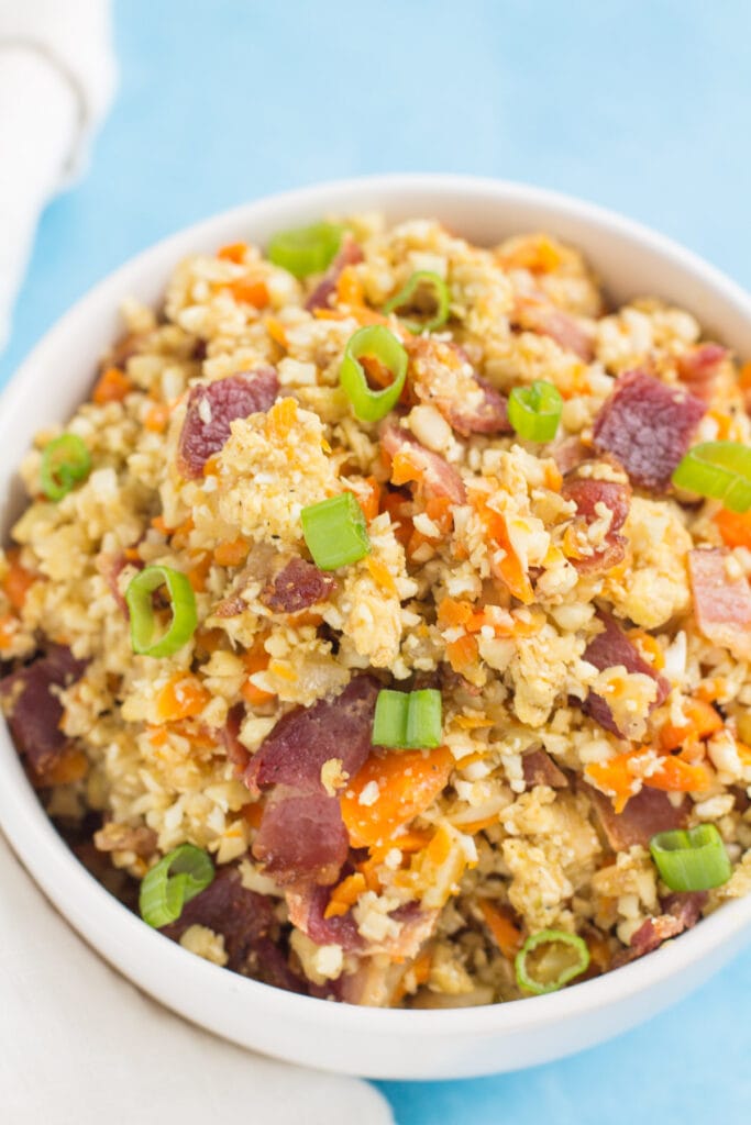 Breakfast Cauliflower Fried Rice in a white bowl on a blue background