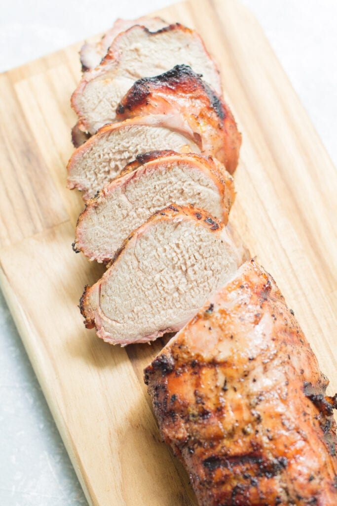 Grilled pork tenderloin on a wooden cutting board