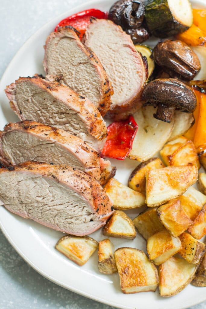grilled pork tenderloin on a plate with potatoes and veggies