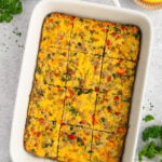 Sausage egg bake that has been sliced in a baking dish on a grey background.