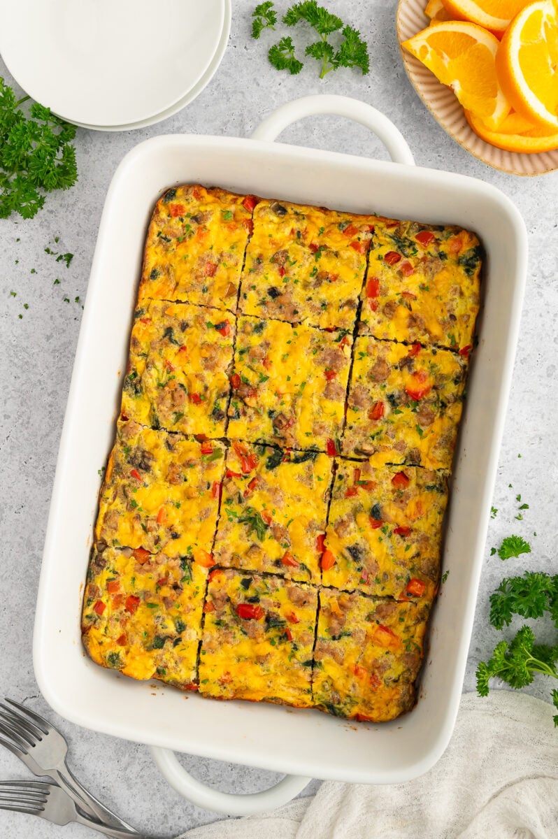 Sausage egg bake that has been sliced in a baking dish on a grey background.