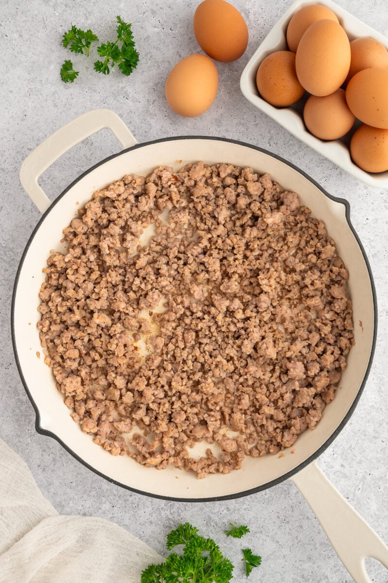 Grounded sausage in a large saute pan with eggs on the side. 