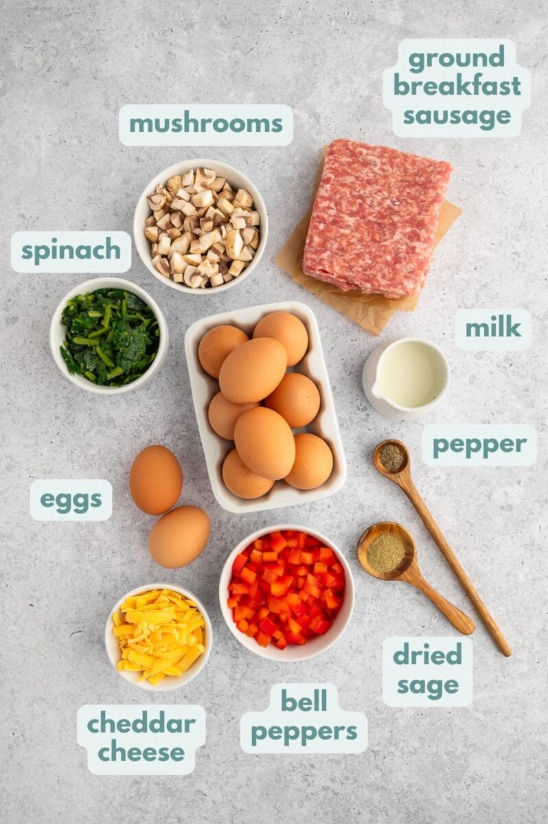 Ingredients for Sausage Egg Bake on a grey background: eggs, almond milk, sausage, bell peppers, cheddar cheese, spinach, spices