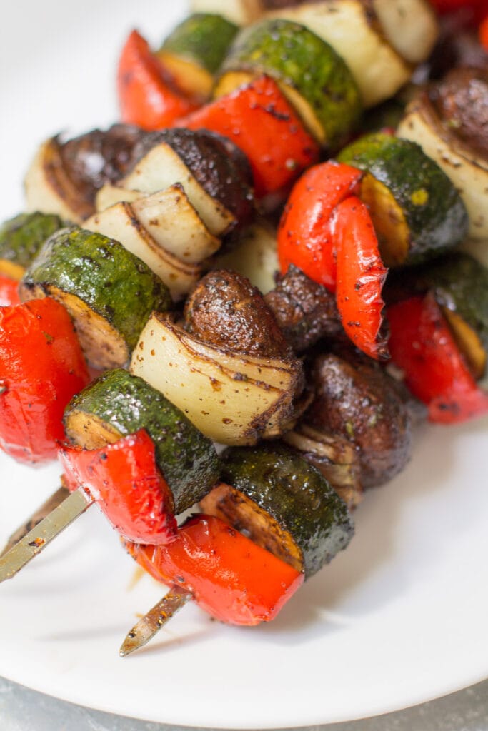 a close up of Grilled Vegetable kebabs on a white plate