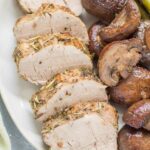 Italian Pork Tenderloin sheet pan dinner on a white plate. pork, mushrooms and asparagus.