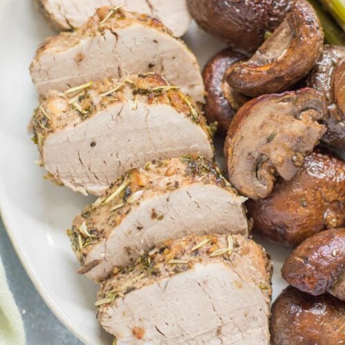 Italian Pork Tenderloin sheet pan dinner on a white plate. pork, mushrooms and asparagus.