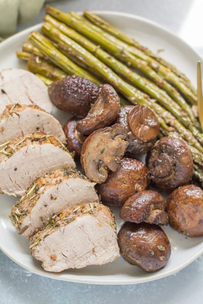 Italian pork tenderloin sheet pan dinner on a white plate with mushrooms and asparagus