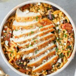 Mediterranean Chicken Orzo on a white dish on a grey background with forks on the side