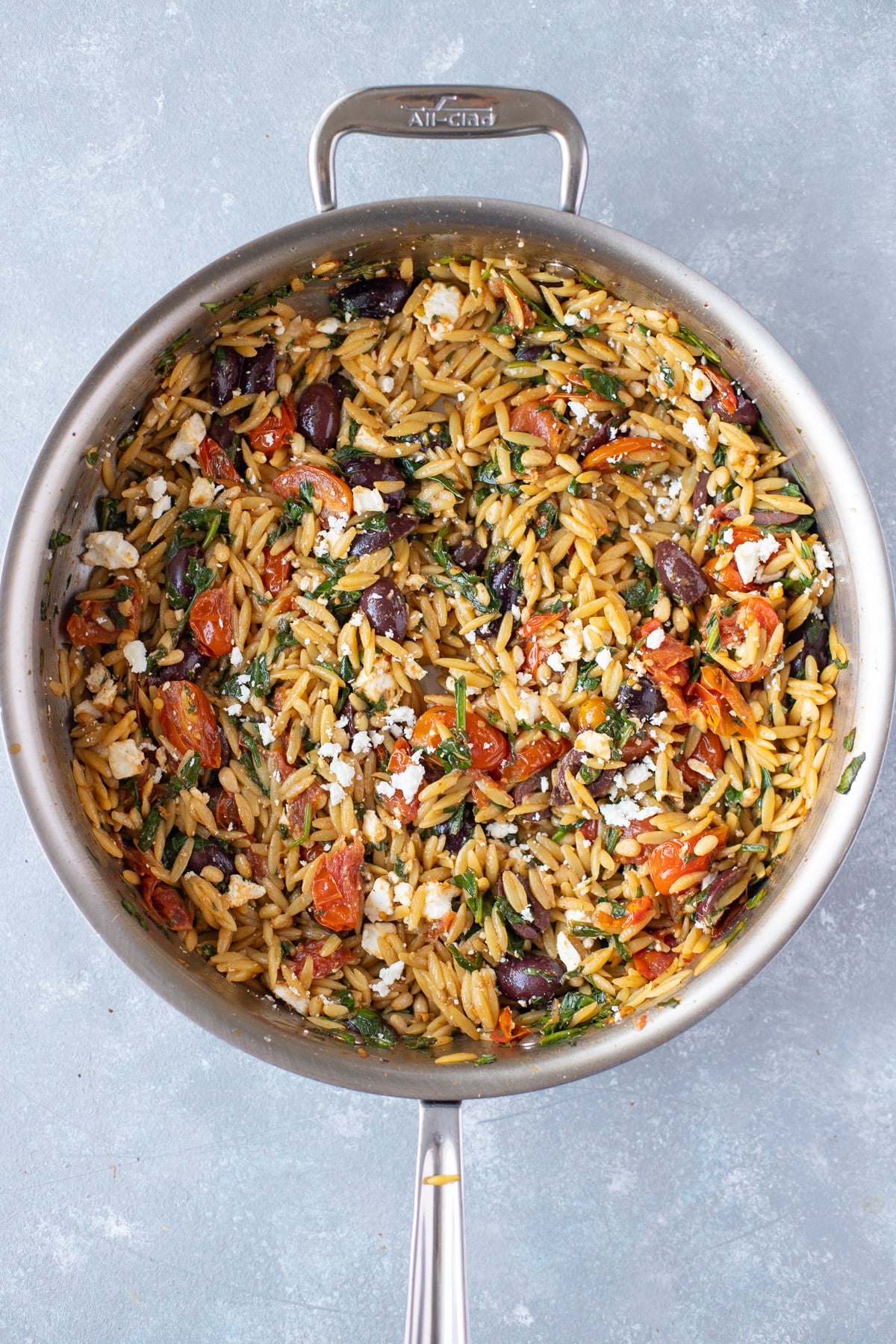 Mediterranean orzo in a pan on a grey background