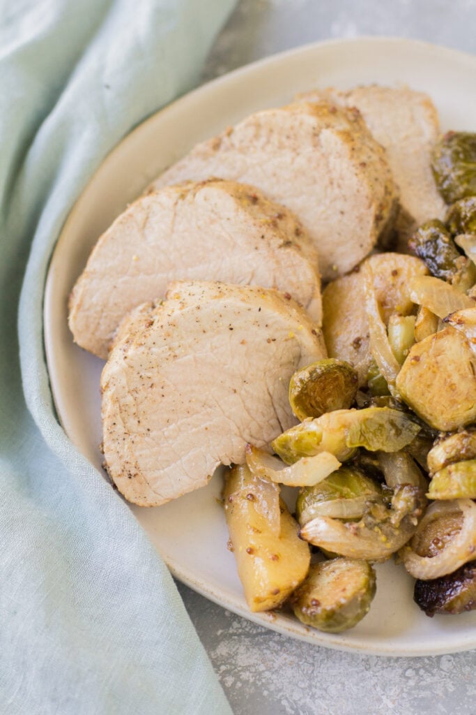 Apple pork tenderloin sliced on a shallow white plate